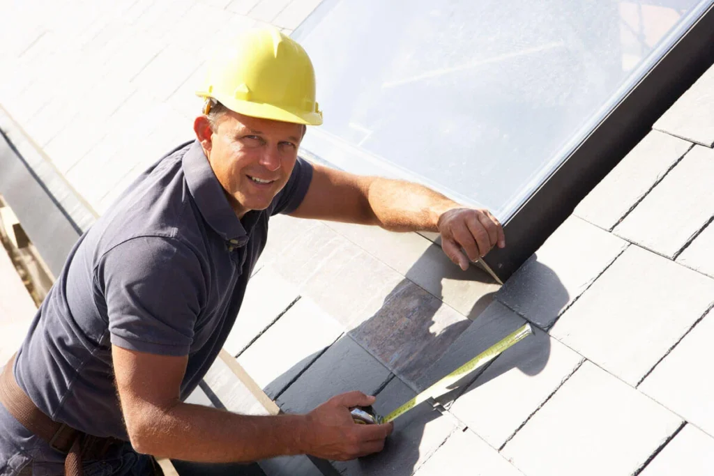 Roofer in a hard hat measuring on a white metal roof