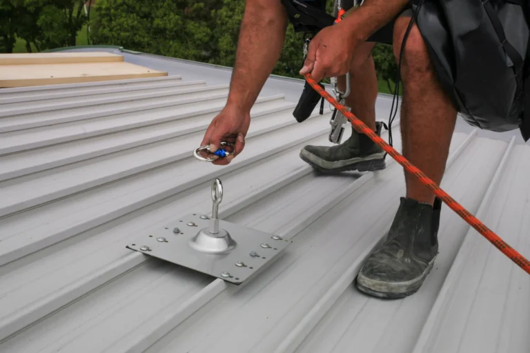 Roofer clipped to a roof anchor with a safety line on a metal roof