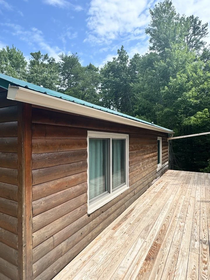 Daniel Hood Roofing installing seamless gutters on a residential cabin for long-lasting water protection.