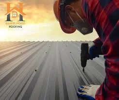 Roofing professional working on a metal roof with a drill, featuring the Daniel Hood Roofing Systems logo.