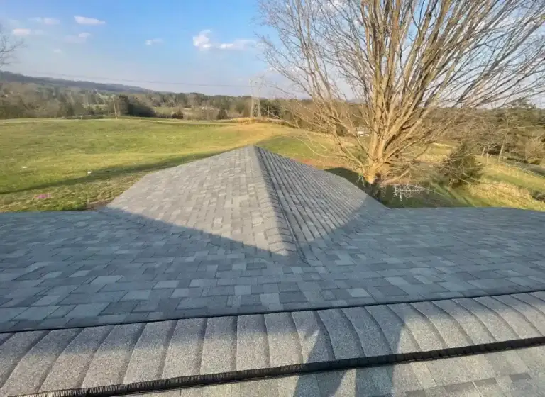 Overhead view of newly installed gray shingle roof with surrounding countryside landscape