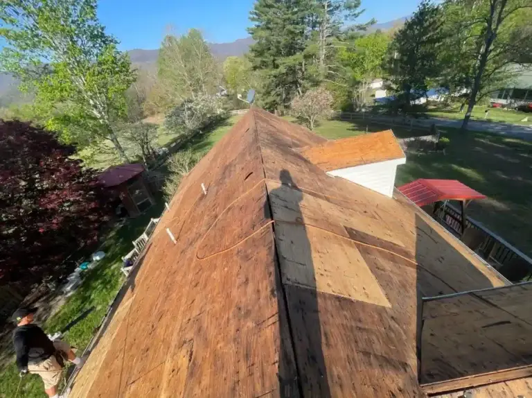 Roof decking exposed during tear-off, with new shingles going on beside it