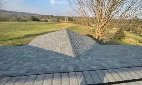 Overhead view of newly installed gray shingle roof with surrounding countryside landscape